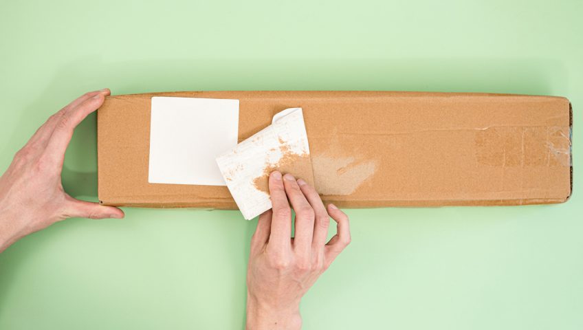 A pressure-sensitive adhesive label peeling off a package.