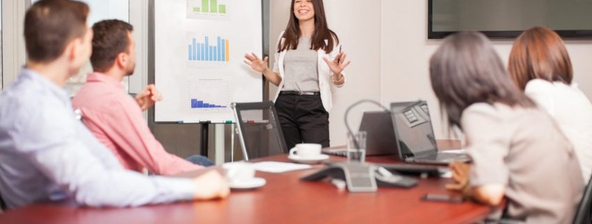 beautiful young latin brunette giving a business presentation to some of her clients in a meeting room