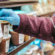 Female consumer wearing gloves and mask, inspecting labeled food packages during COVID pandemic.
