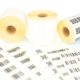 White label rolls and printed barcodes isolated on white background with shadow reflection. White reels of labels for printers. Labels for direct thermal or thermal transfer printing. Barcode samples.