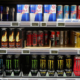 Three shelves in a supermarket full of various energy drink products displaying labels that meet legal requirements.