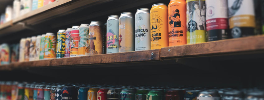 Three shelves in a retail store full of various craft beer cans with shrink sleeve and pressure-sensitive can wraps.