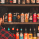 Male consumer staring at several shelves full of craft beer options and observing label design.