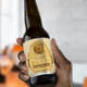 Hand holding craft beer bottle with creased, peeling label.