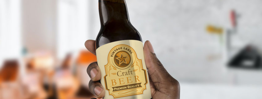 Hand holding craft beer bottle with creased, peeling label.