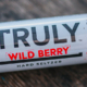 Truly wild berry hard seltzer can laying faceup on wooden surface.